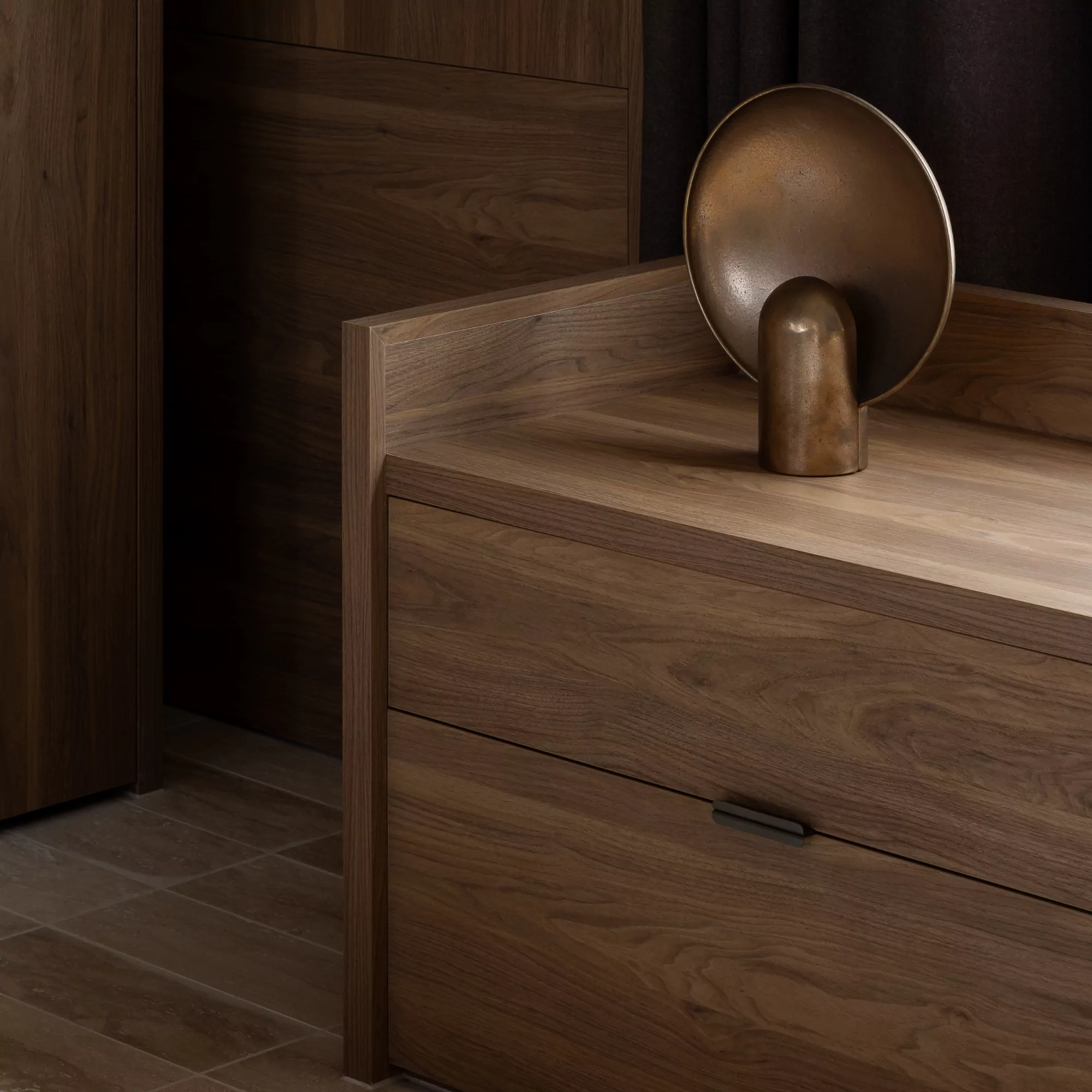 A walnut timber cabinet with a minimalist lip pull by Castella in bronze, along with a solid brass Henry Wilson lamp — showcasing how different materials and finishes compliment each other